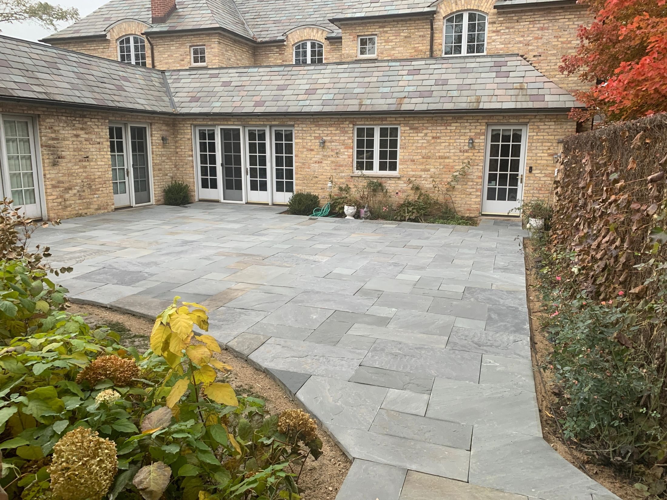 Completed bluestone patio beside a brick home